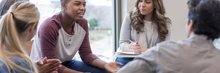 Young adult speaks to a group sitting in a circle