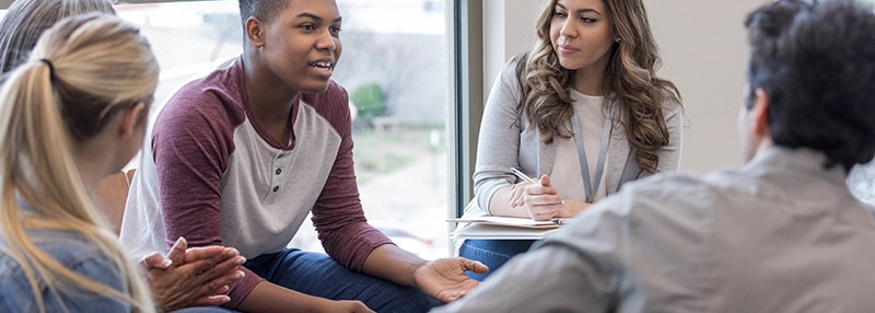 Young adult speaks to a group sitting in a circle