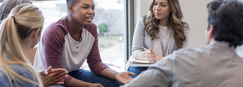 Young adult speaks to a group sitting in a circle