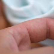 Adult holding baby's hand in hospital