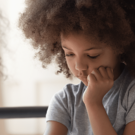 Healthcare professional speaking to a young child who has their head in their hand and is looking down