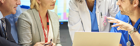 A group of colleagues standing around a laptop