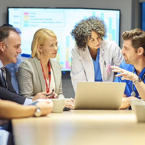 A group of colleagues standing around a laptop