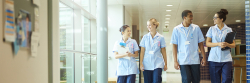 Group of four nurses walking along a hospital corridor