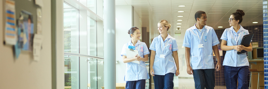 Group of four nurses walking along a hospital corridor