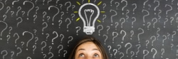 A person surrounded by question marks drawn around them and a light bulb drawn above their head