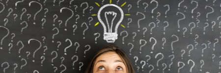 A person surrounded by question marks drawn around them and a light bulb drawn above their head