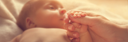 Mother holding the hand of her newborn baby