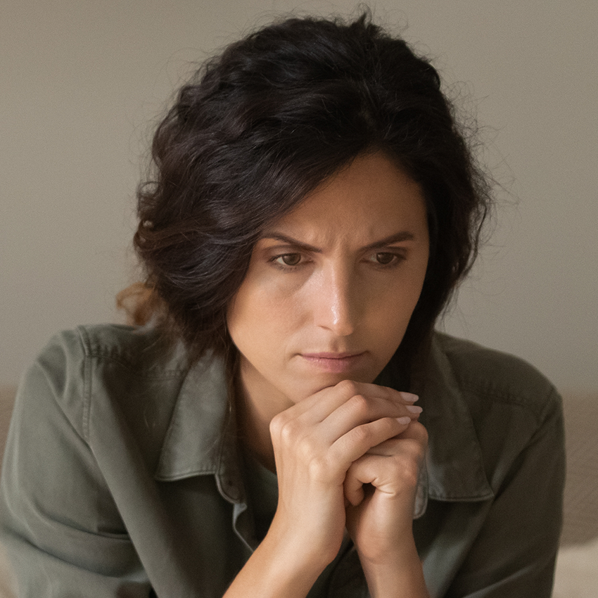 Woman with hands clasped and head on hands